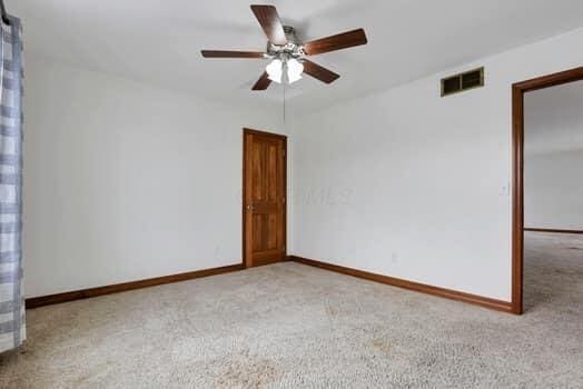 carpeted empty room with visible vents, baseboards, and a ceiling fan