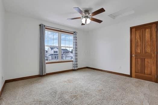 carpeted empty room featuring baseboards and ceiling fan