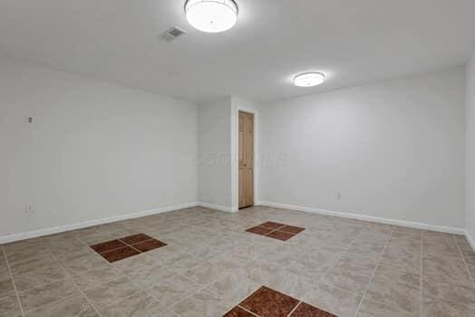 unfurnished room featuring tile patterned flooring, visible vents, and baseboards