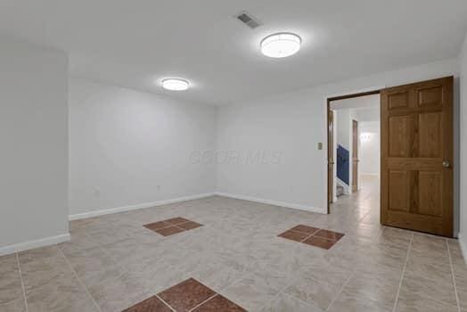 tiled spare room featuring visible vents and baseboards