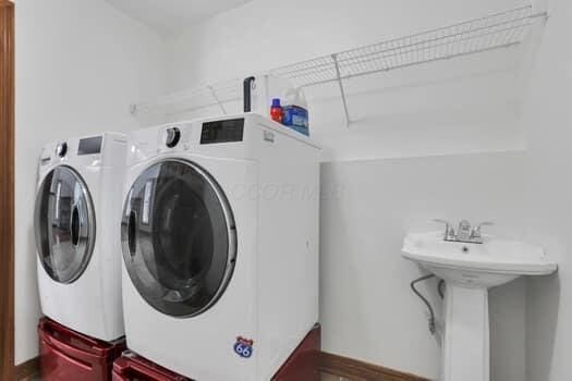 laundry area featuring washer and dryer, laundry area, baseboards, and a sink