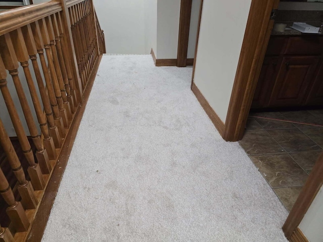 hall with baseboards and dark colored carpet