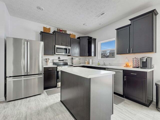 kitchen featuring visible vents, a kitchen island, appliances with stainless steel finishes, light countertops, and a textured ceiling