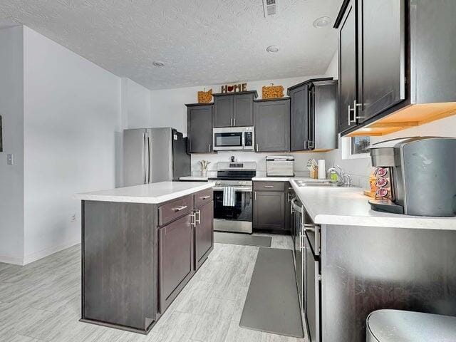 kitchen featuring stainless steel appliances, light countertops, visible vents, a sink, and a kitchen island