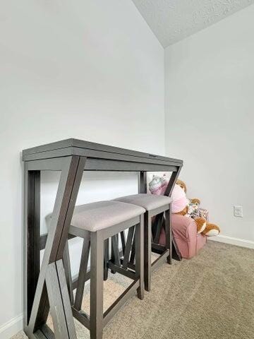 dining area with a textured ceiling, baseboards, lofted ceiling, and light colored carpet