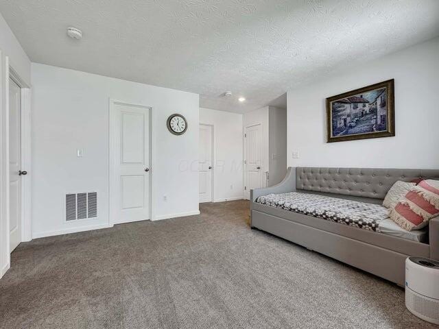 living room with a textured ceiling, carpet, visible vents, and baseboards