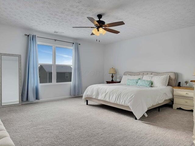 bedroom with a textured ceiling, carpet flooring, visible vents, and a ceiling fan