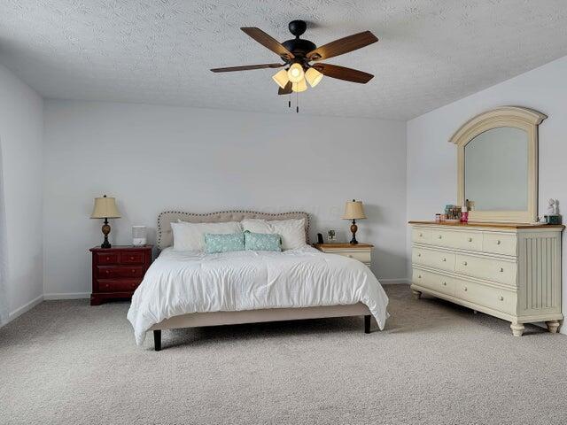 bedroom featuring carpet floors, ceiling fan, a textured ceiling, and baseboards