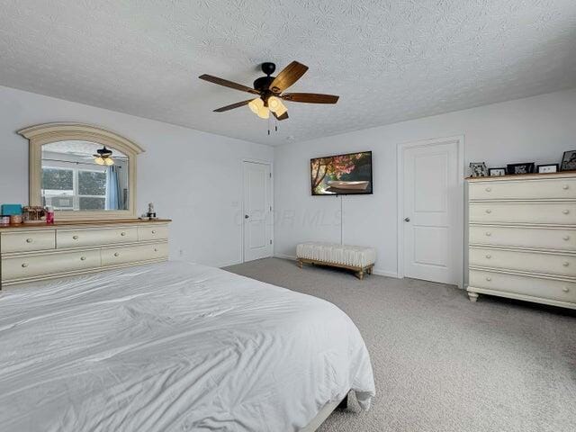 carpeted bedroom with a textured ceiling and a ceiling fan