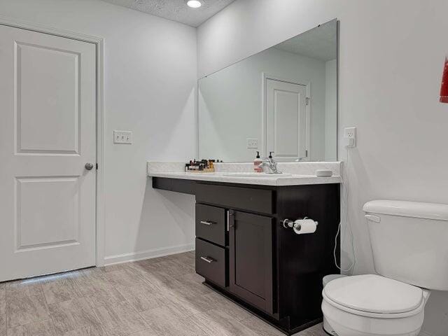 bathroom with toilet, baseboards, a textured ceiling, and vanity