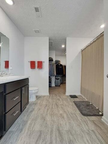 full bathroom featuring baseboards, toilet, wood finished floors, a textured ceiling, and vanity