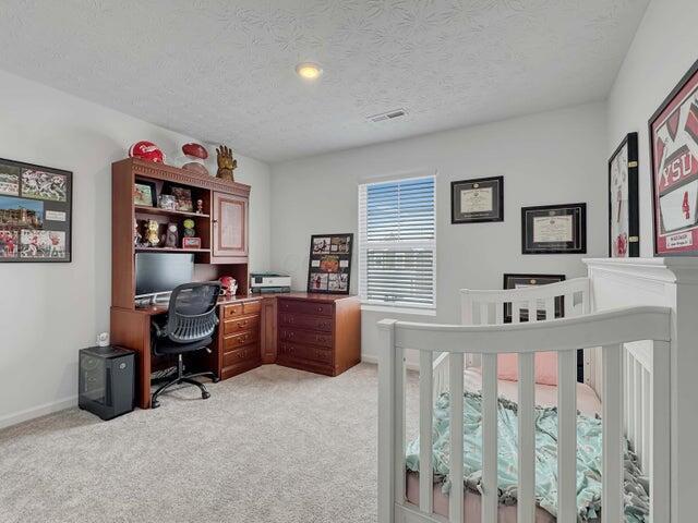 bedroom with baseboards, visible vents, a textured ceiling, and light colored carpet