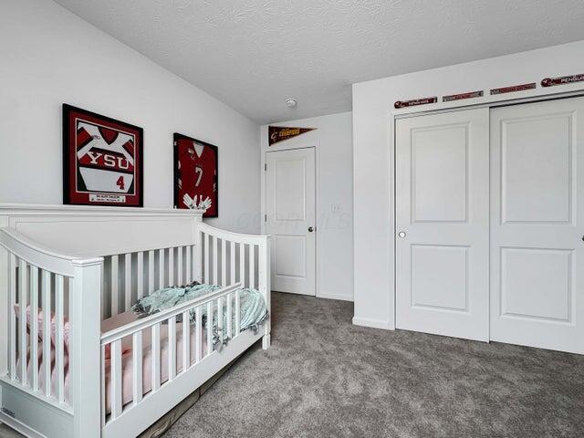 bedroom featuring carpet floors, a closet, a textured ceiling, and a crib