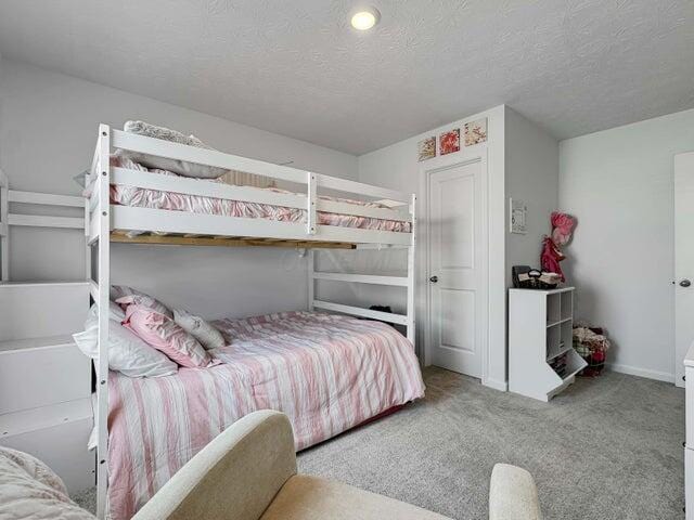 carpeted bedroom featuring a textured ceiling and baseboards