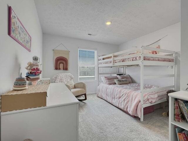 carpeted bedroom featuring a textured ceiling and visible vents