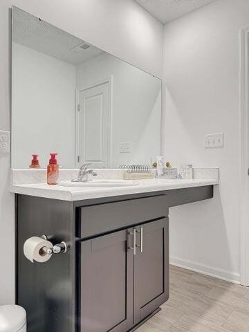 bathroom with baseboards, vanity, toilet, and a textured ceiling