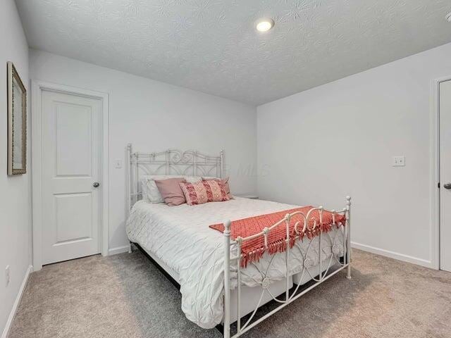 bedroom with carpet, baseboards, and a textured ceiling