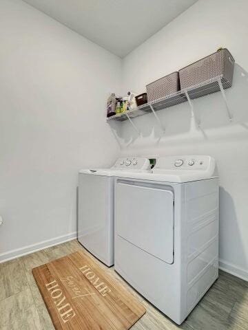 clothes washing area with baseboards, laundry area, light wood finished floors, and washer and dryer