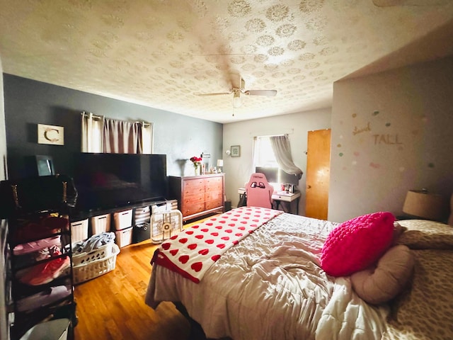 bedroom with ceiling fan, a textured ceiling, and hardwood / wood-style flooring