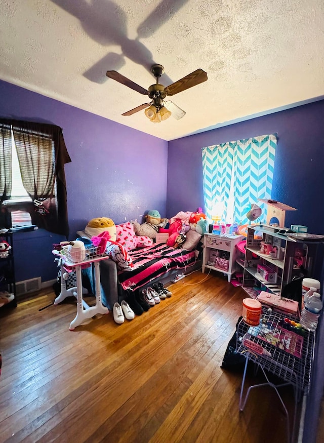 bedroom with ceiling fan, a textured ceiling, and hardwood / wood-style flooring