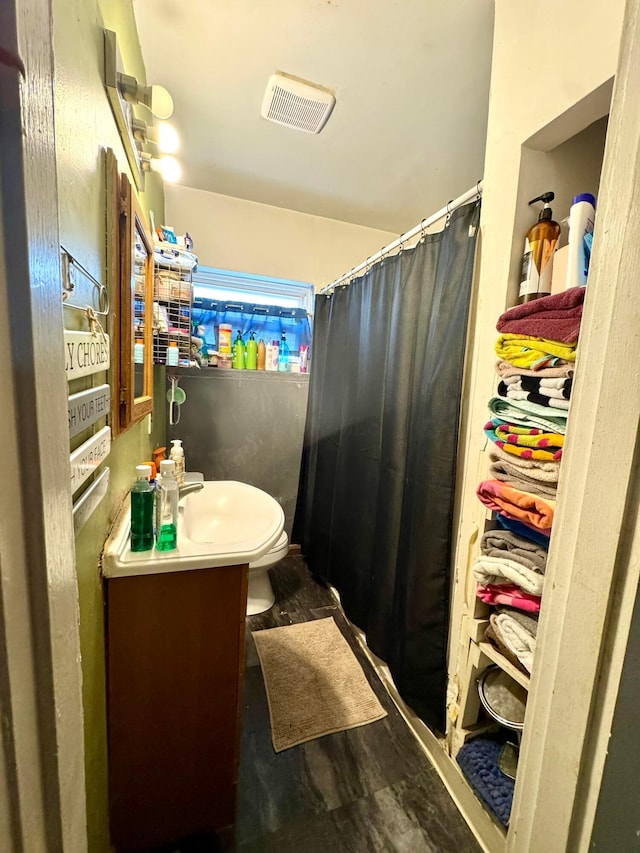 bathroom with walk in shower, vanity, and toilet