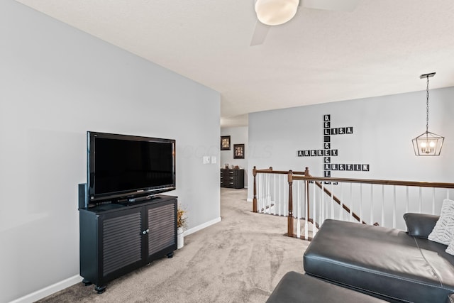 carpeted living room with ceiling fan with notable chandelier