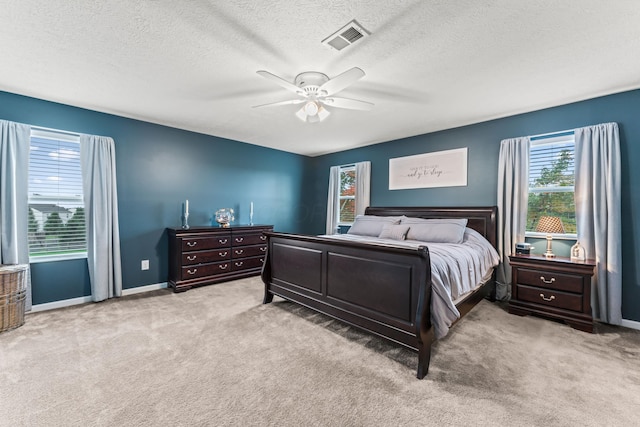 bedroom with ceiling fan, light colored carpet, and a textured ceiling