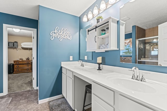 bathroom with a textured ceiling, an enclosed shower, and vanity