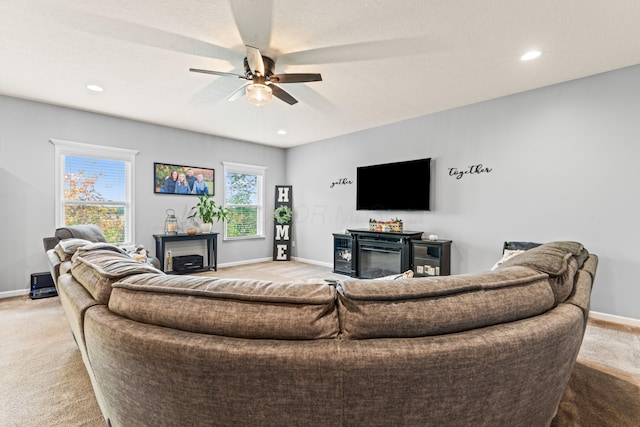 carpeted living room featuring a fireplace and ceiling fan