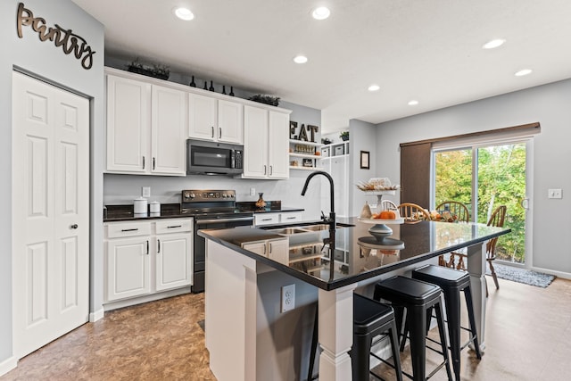 kitchen with sink, stainless steel appliances, white cabinets, and a kitchen island with sink