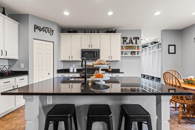 kitchen with white cabinets, a kitchen island with sink, and sink