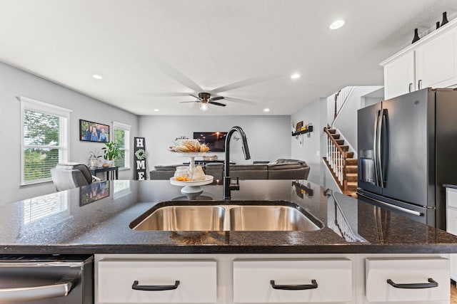 kitchen featuring sink, white cabinets, dark stone countertops, a center island with sink, and stainless steel appliances