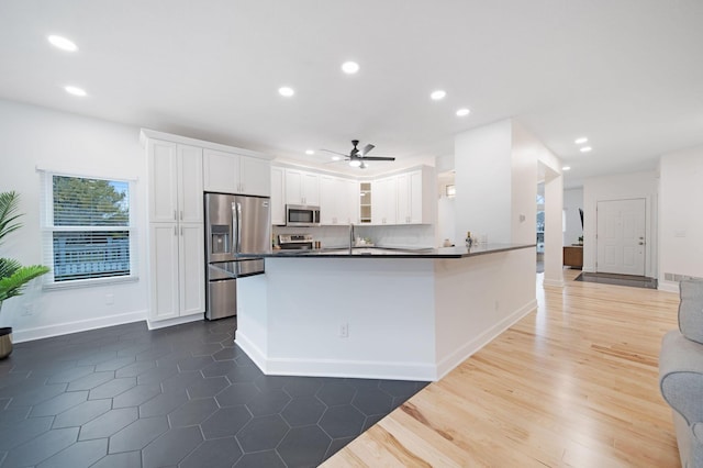 kitchen with ceiling fan, appliances with stainless steel finishes, dark hardwood / wood-style floors, white cabinets, and kitchen peninsula