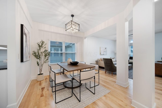 dining area with light hardwood / wood-style floors and a notable chandelier