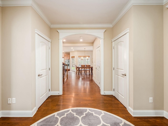 corridor with dark hardwood / wood-style flooring, crown molding, and a chandelier