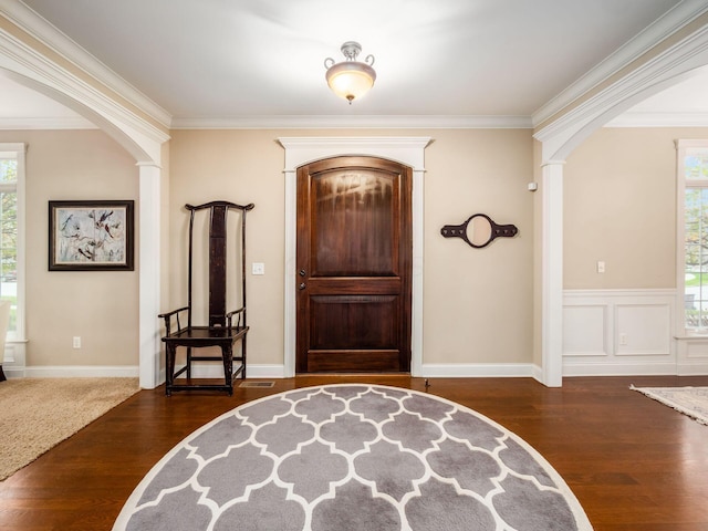 foyer with dark hardwood / wood-style flooring, crown molding, and decorative columns