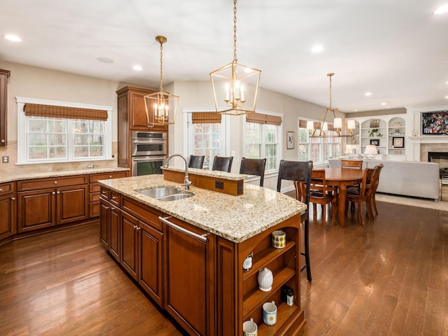 kitchen featuring a breakfast bar area, a center island with sink, double oven, pendant lighting, and sink