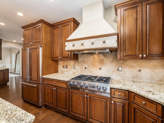 kitchen featuring paneled built in refrigerator, stainless steel gas cooktop, custom range hood, decorative backsplash, and dark hardwood / wood-style floors