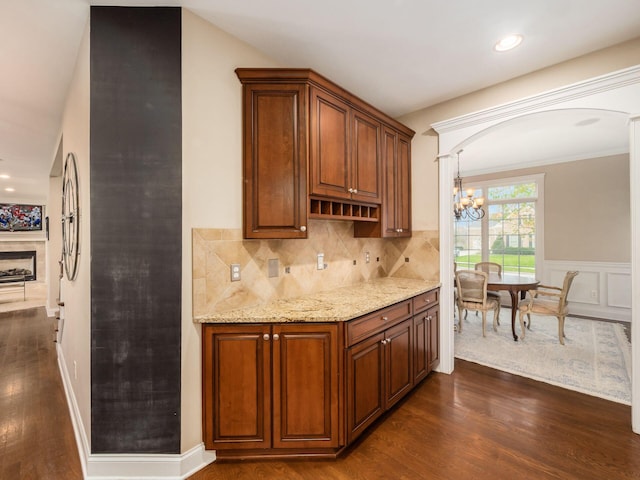 kitchen featuring a chandelier, dark hardwood / wood-style floors, backsplash, and light stone countertops