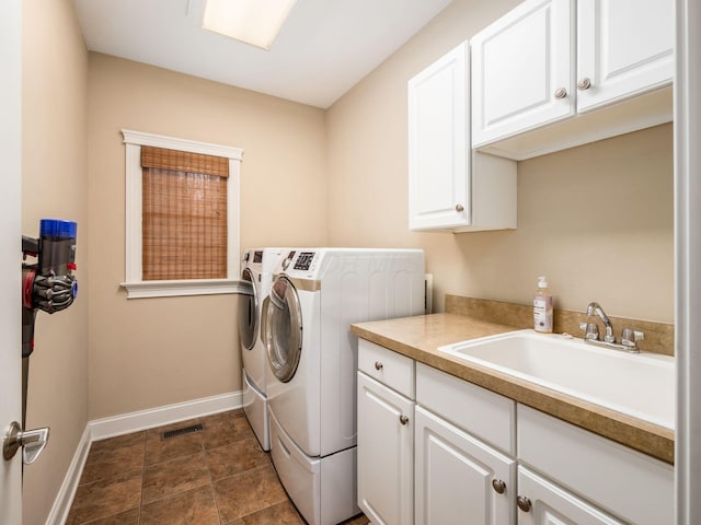 clothes washing area with sink, cabinets, and independent washer and dryer