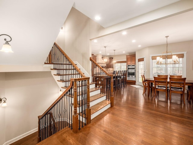 stairs featuring a notable chandelier and wood-type flooring