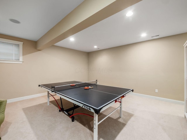 recreation room featuring light colored carpet and beamed ceiling