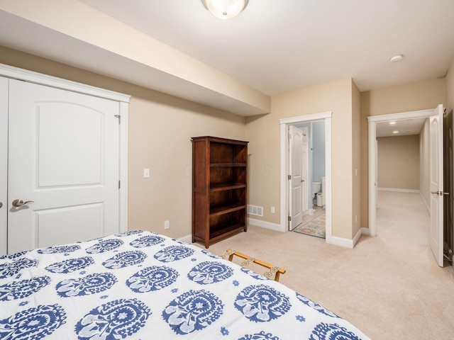 bedroom with connected bathroom and light carpet