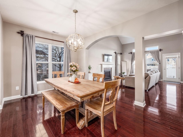 dining space featuring vaulted ceiling, dark hardwood / wood-style flooring, and an inviting chandelier