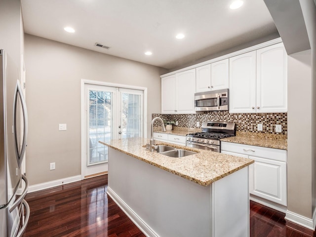 kitchen featuring sink, white cabinetry, a kitchen island with sink, stainless steel appliances, and light stone counters