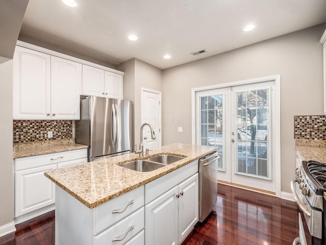 kitchen featuring white cabinetry, a center island with sink, appliances with stainless steel finishes, light stone countertops, and sink