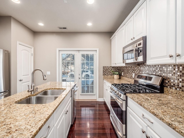 kitchen with light stone counters, sink, white cabinetry, and stainless steel appliances