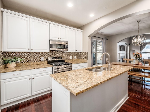 kitchen featuring white cabinetry, a center island with sink, appliances with stainless steel finishes, pendant lighting, and sink