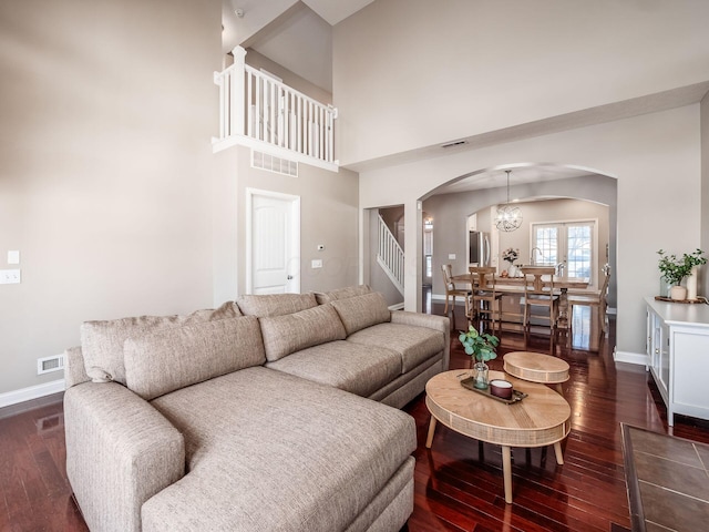 living room featuring a high ceiling, an inviting chandelier, and dark hardwood / wood-style floors