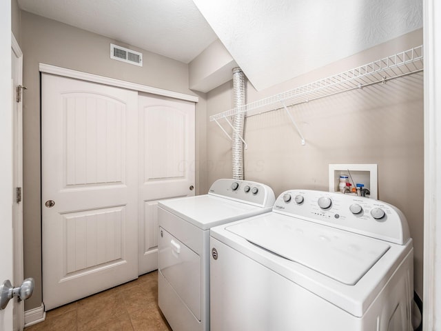 laundry area with light tile patterned floors and washing machine and clothes dryer